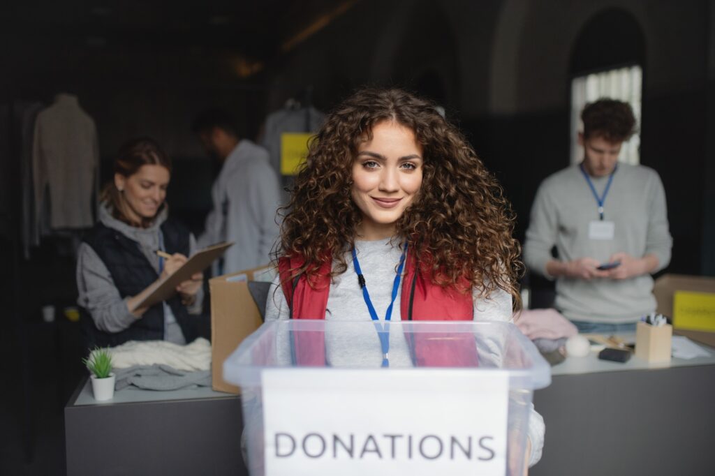 Woman volunteer working in community charity donation center, looking at camera